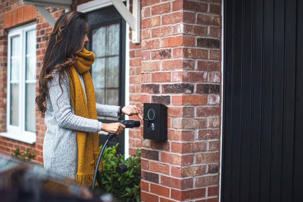 Wall-mounted EV charger on the brick exterior of a suburban home
