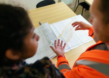 pexels-photo-3862384-3862384 Two engineers reviewing construction blueprints on a table in an office setting.